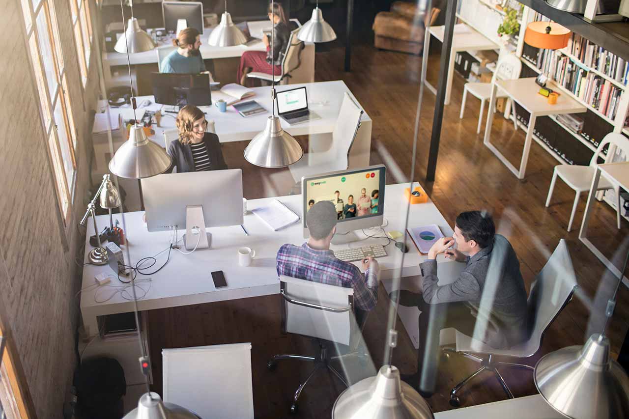 Modern office environment with professionals collaborating at desks, using computers and discussing workflows. EasyRedir now offers the ability to automatically secure redirect links with HTTPS.