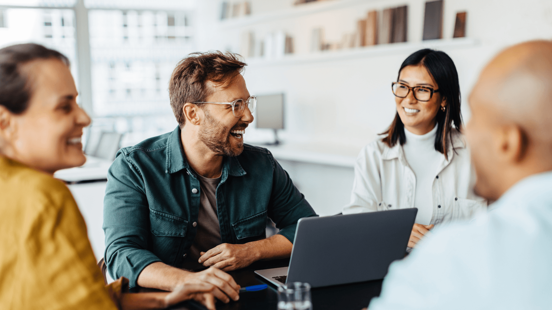 Photo of a group of people surrounding a laptop at an office.