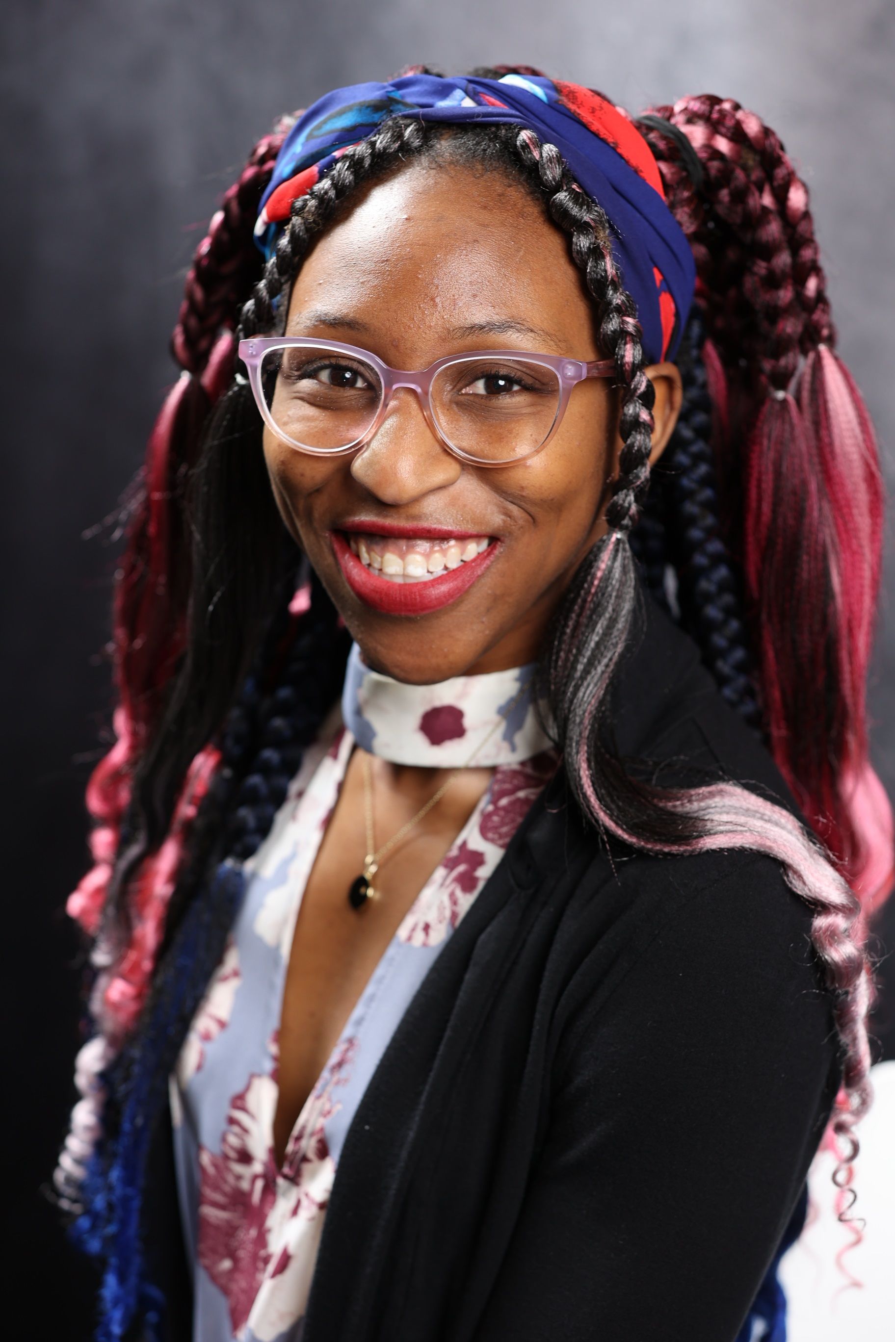 Man in black shirt sitting in front of a black flat screen computer monitor looking at code. Woman in striped shirt sitting beside black flat screen computer monitor, across from the man.