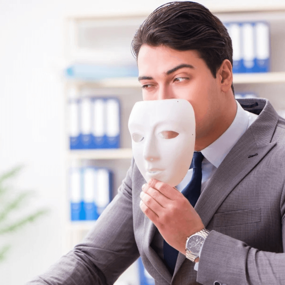 Person holding a mask to their face in front of a computer.